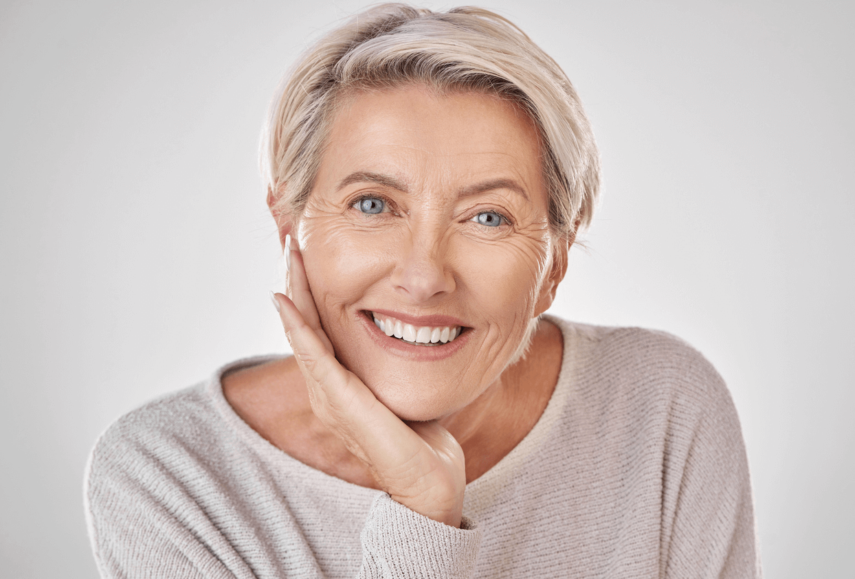 A mature woman smiling broadly showing her natural-looking teeth.
