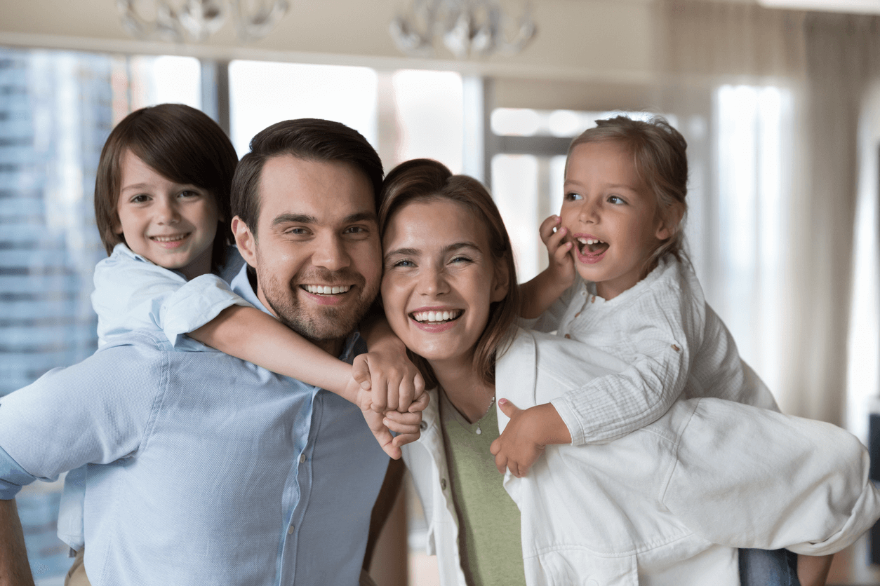 Smiling young parents piggy-backing their two kids.